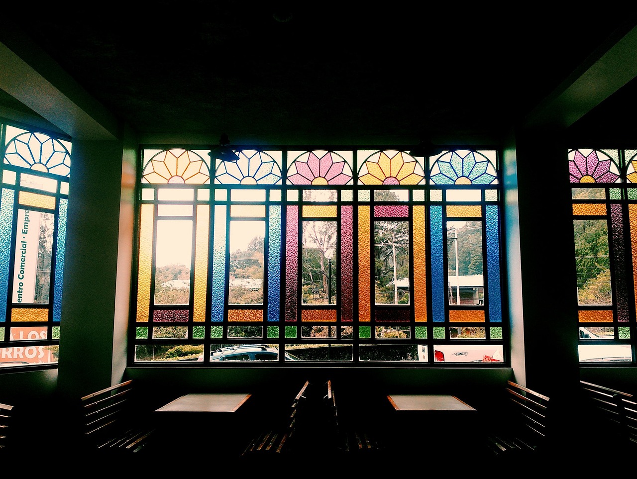 coffee-shop-1569716_1280.jpg Interior of a coffee shop with wooden benches, looking out through stained glass window