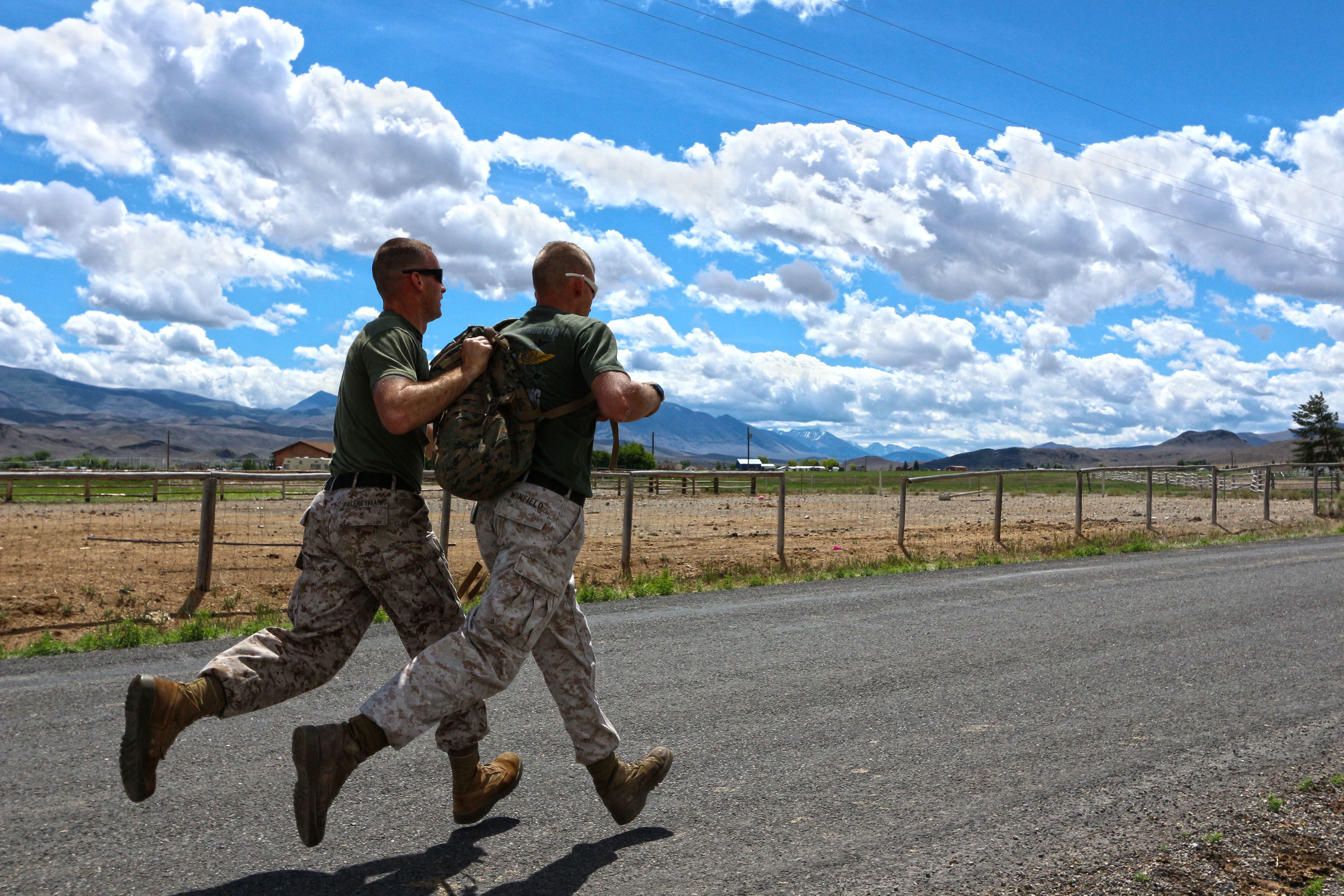 rucking.jpg Two soldiers running on asphalt, with one holding up the other's backpack