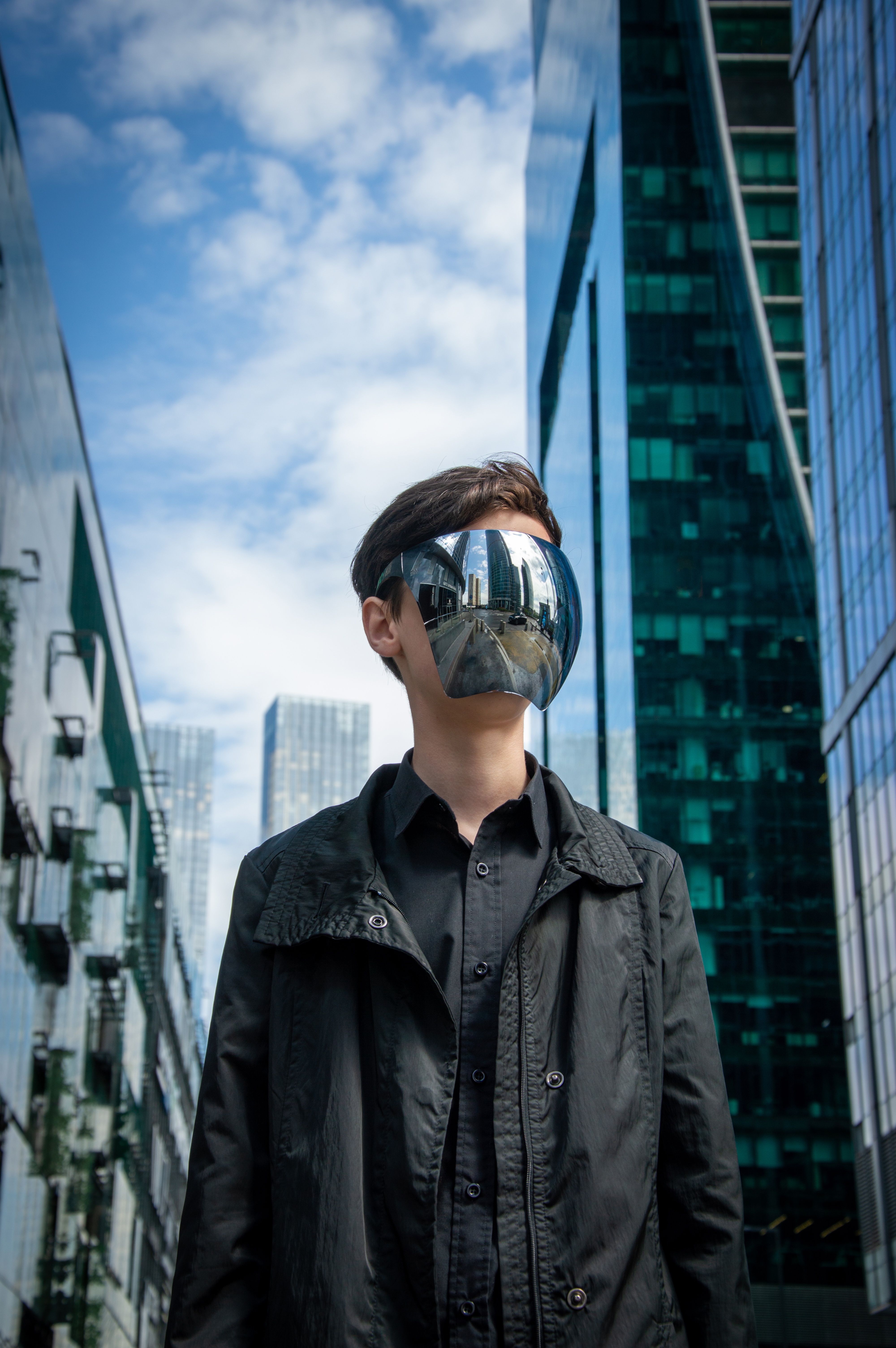 A man in an urban landscape, wearing a mirrored VR helmet