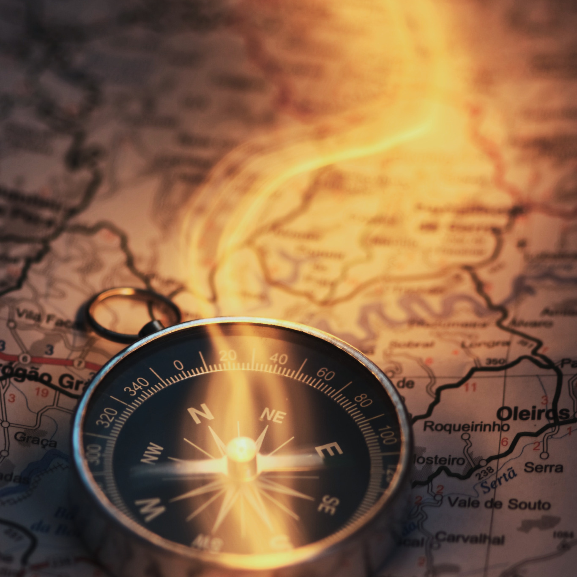 A compass lying on a map, with a stream of glowing magic eminating from it