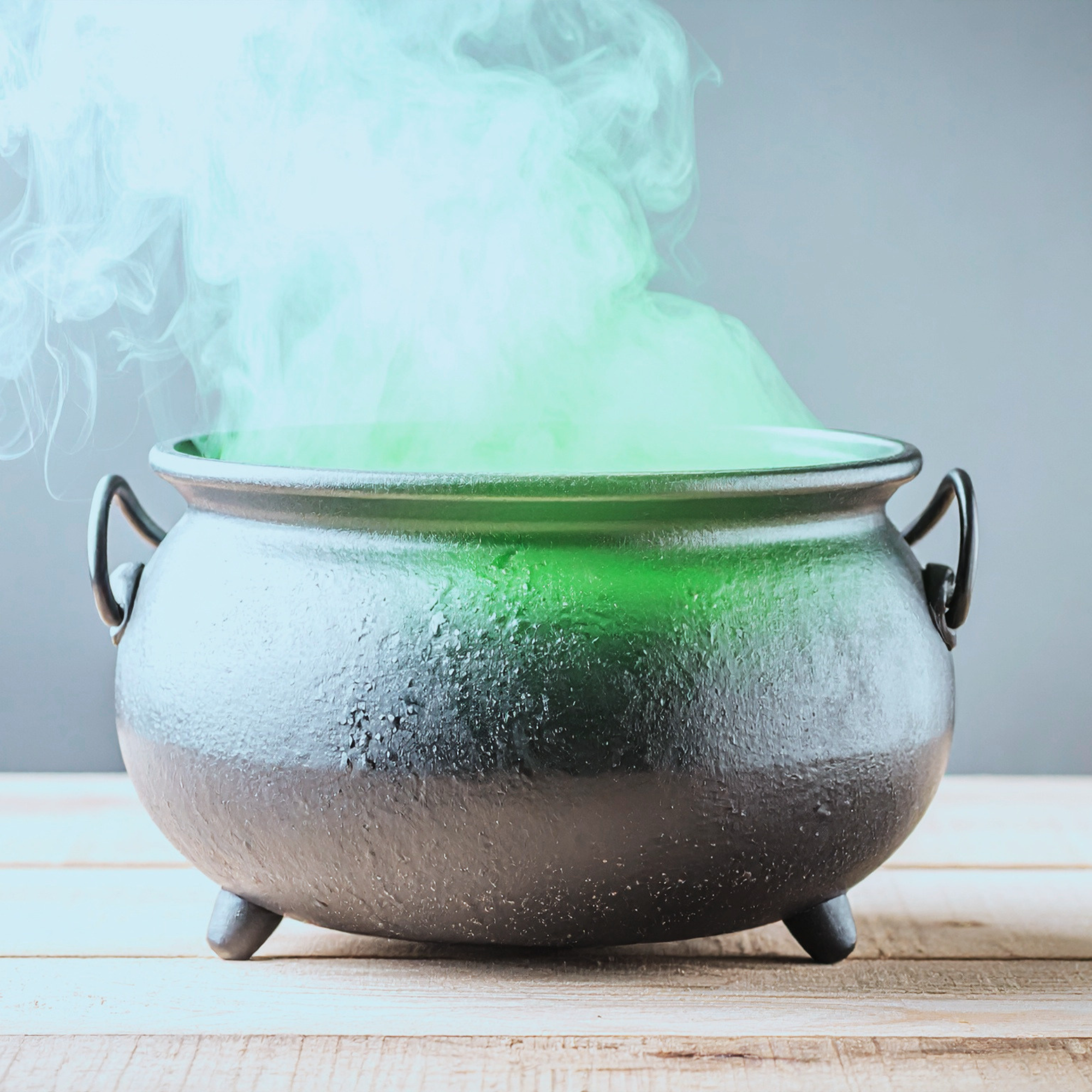 A steaming iron cauldron on a wood table, emitting greenish smoke